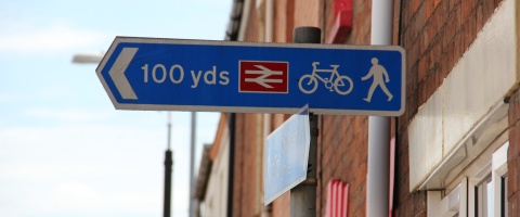 Pedestrian and cyclist direction sign towards train station with approximate distance
